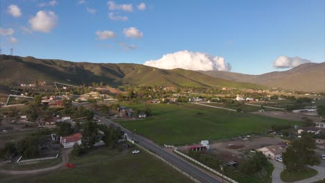 Rural-United-states-countryside-flyover-aerial-view-across-small-town-community-development-residential-area-under-mountain-landscape