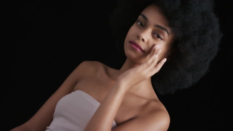 portrait attractive african american woman touching face with hands caressing smooth healthy skin complexion enjoying perfect natural beauty funky afro on black background