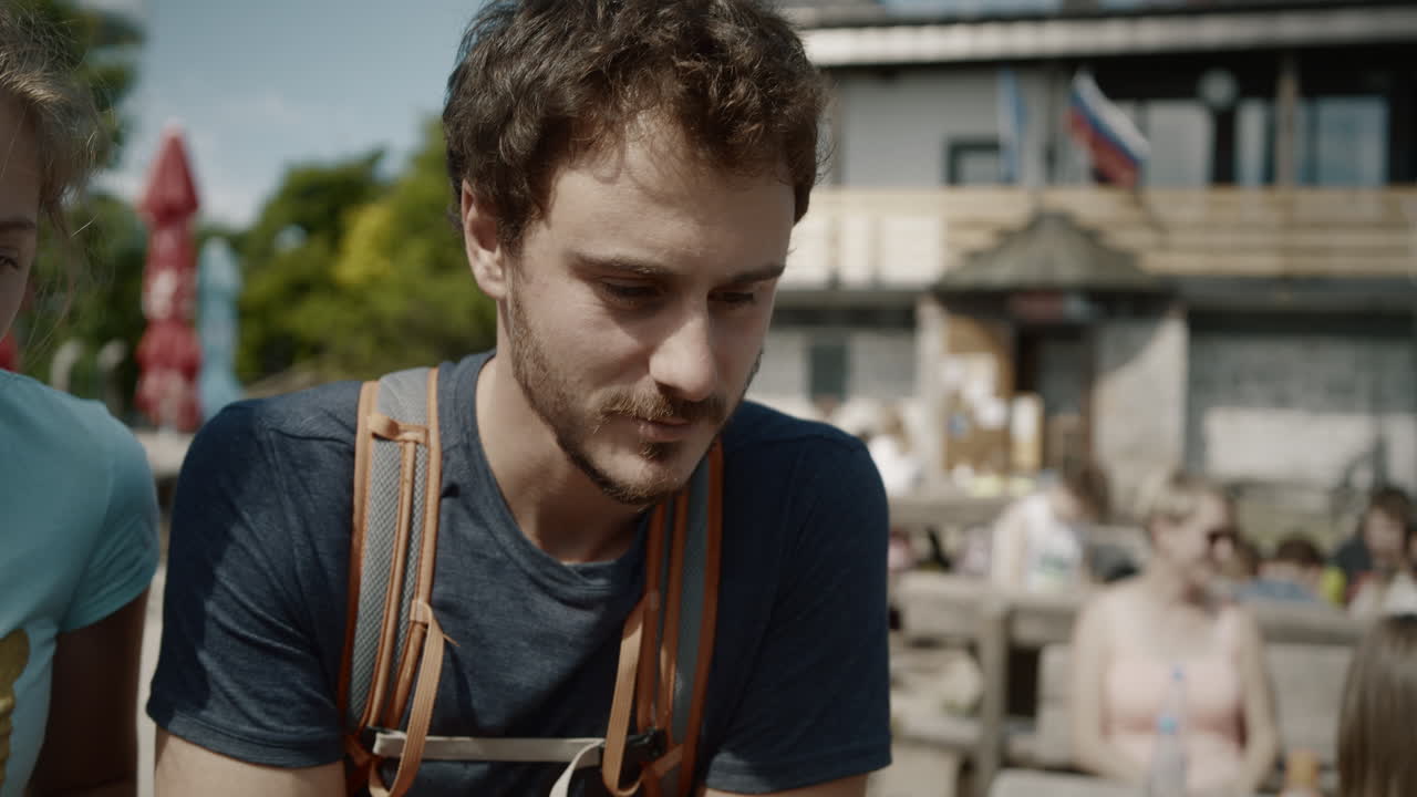 방향이 표시된 테이블을 바라보는 젊은 등산객, 배경에 두 개의 깃발이 있는 산장, 케이터링 우산