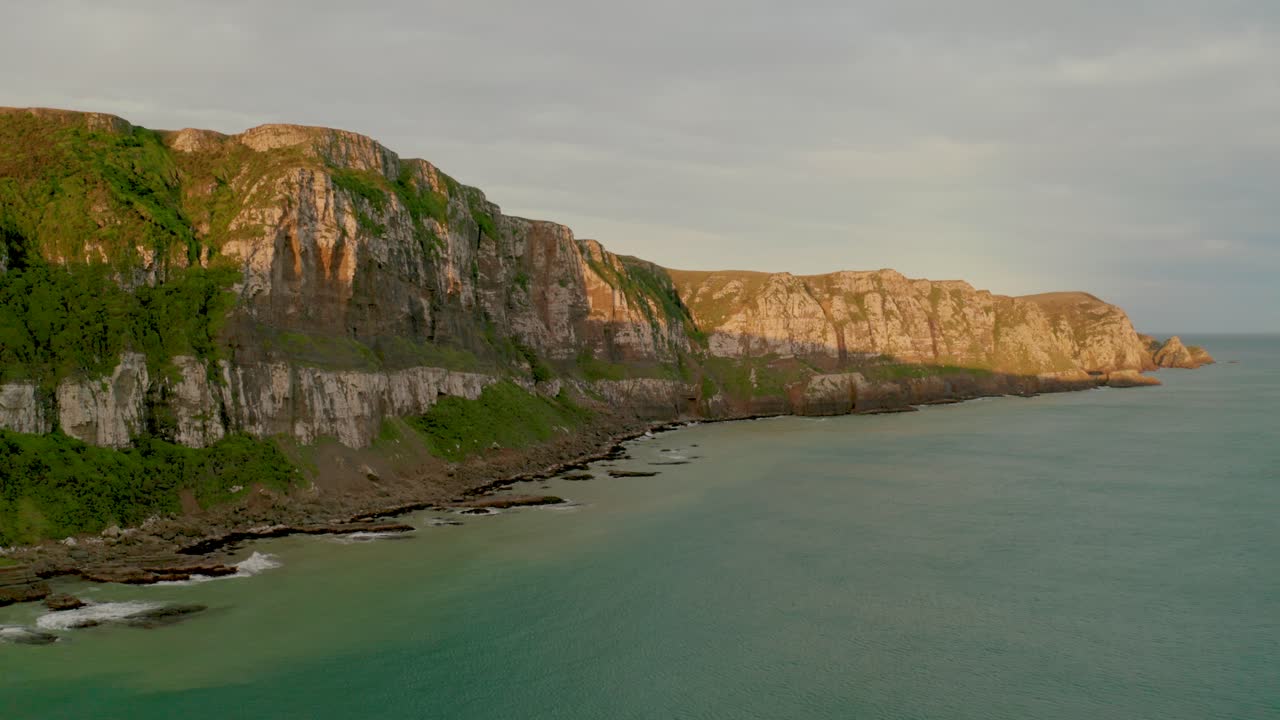toma aérea de los rayos solares golpeando la cima de los acantilados a lo largo de la costa en nueva zelanda