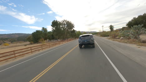 FPV-drone-chasing-shot-of-new-futuristic-police-car-traveling-along-the-road