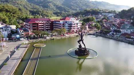 aerial view of a monumental statue in a lake with cityscape and mountains