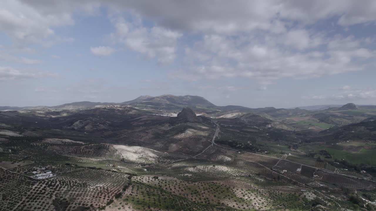 Aerial 4K footage of Olvera, Spain, captured with a DJI drone at 30fps. A cinematic view of open meadows with a stunning castle atop the mountain in the background.