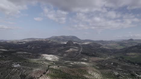 aerial 4k footage of olvera, spain, captured with a dji drone at 30fps. a cinematic view of open meadows with a stunning castle atop the mountain in the background.