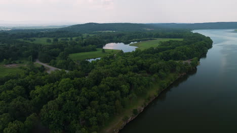 Spadra-park-forest-by-Arkansas-river,-aerial-drone-view-with-moving-train