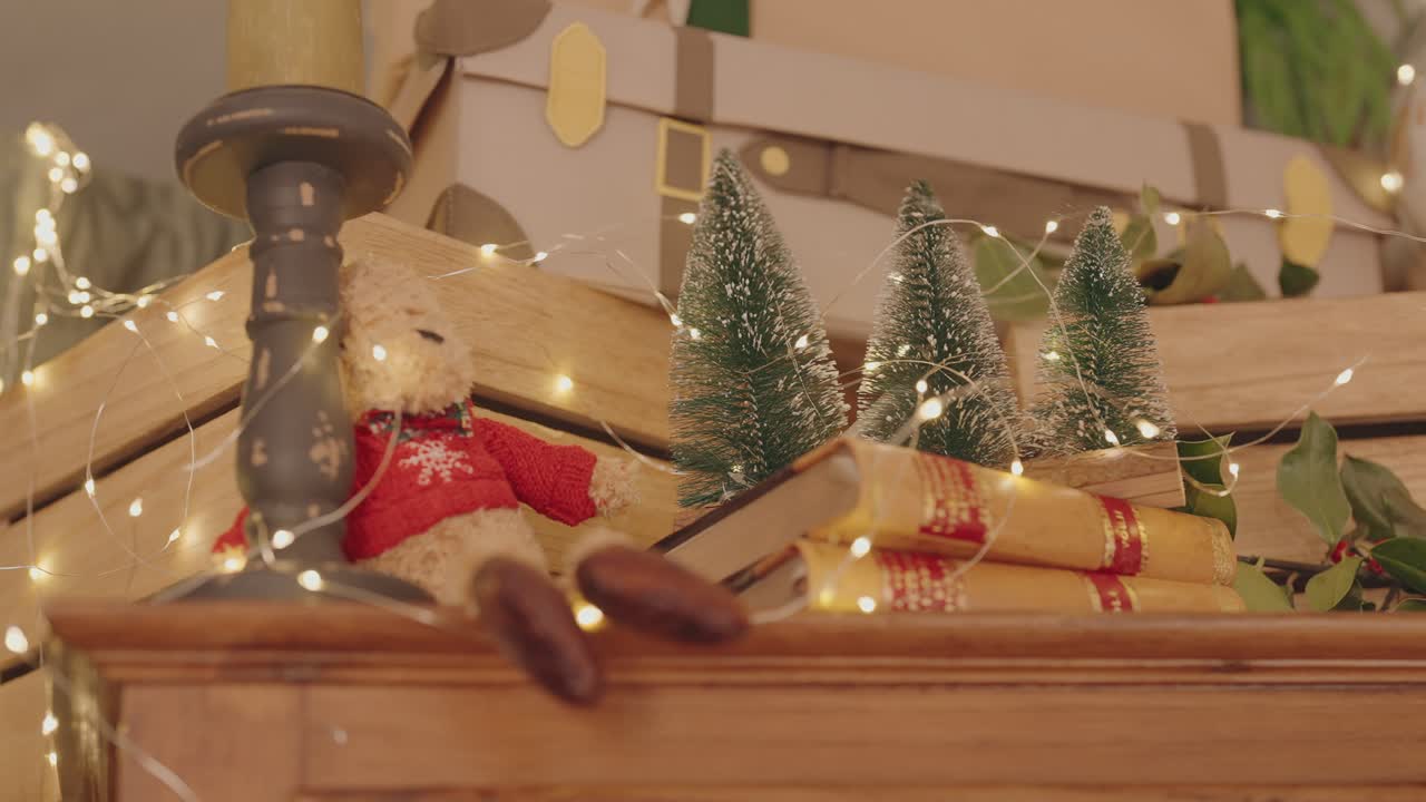 adorno festivo con un oso de peluche con un jersey rojo, libros antiguos, miniárboles de Navidad y luces cálidas