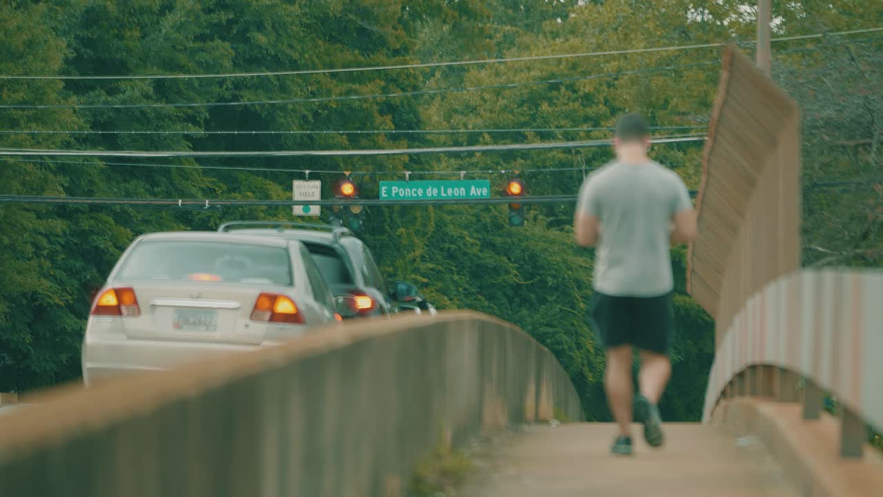 한 남자가 교통량이 많은 분주한 다리를 건너고 있습니다.