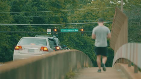 A-Man-Walks-Across-A-Busy-Bridge-Loaded-With-Traffic