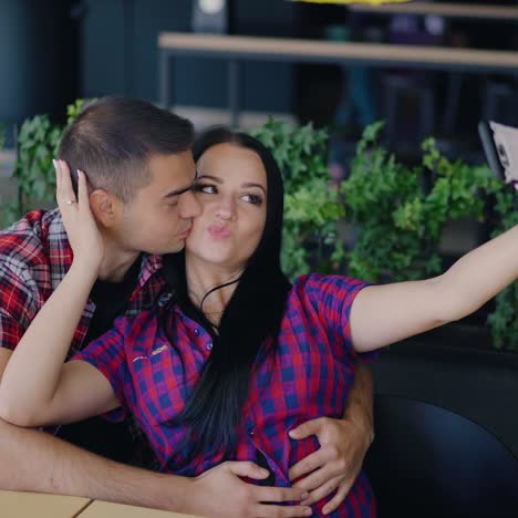 ein verliebtes paar küsst sich und macht ein foto im café auf dem hintergrund des innenraums. selfie