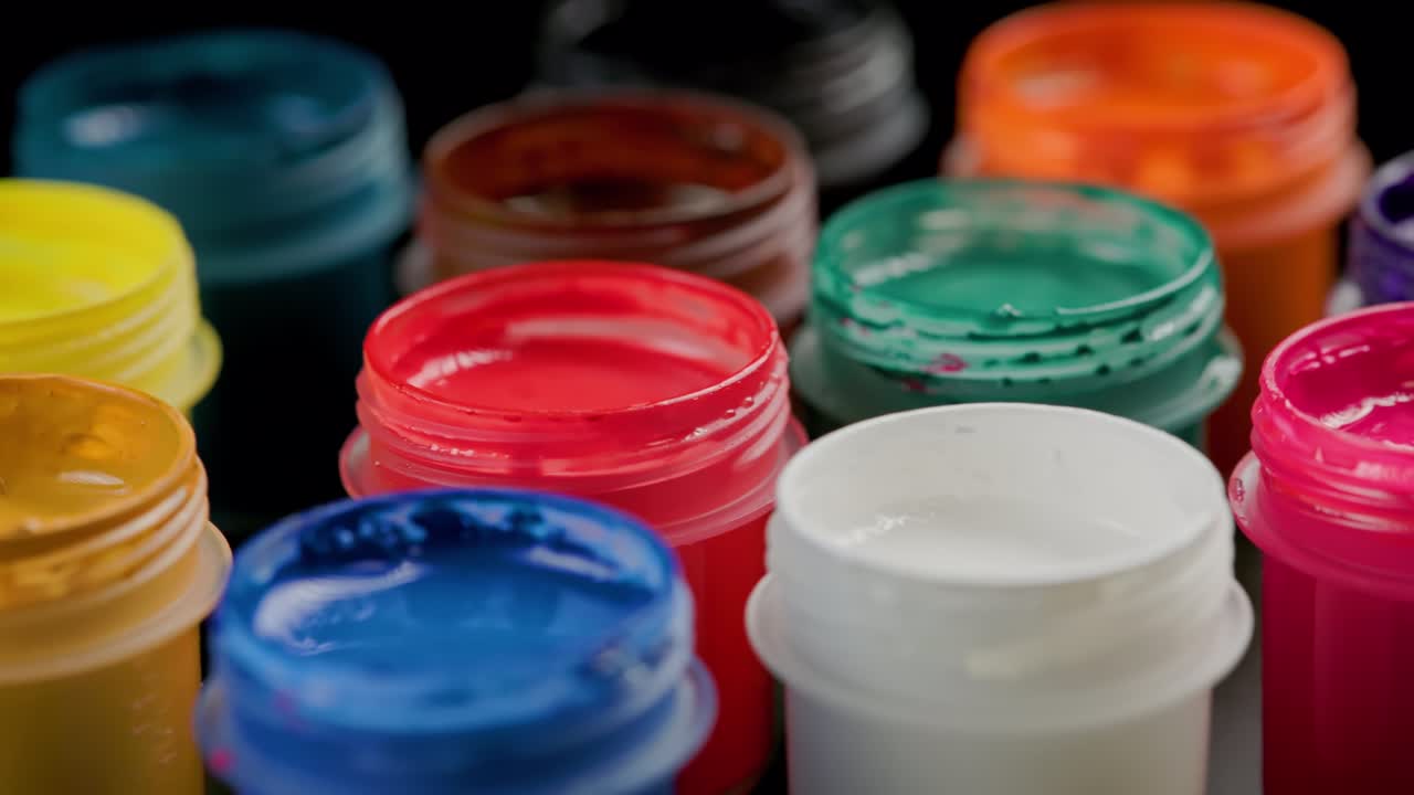 fondo de primer plano giratorio en bucle de pequeños frascos de pintura de gouache abiertos