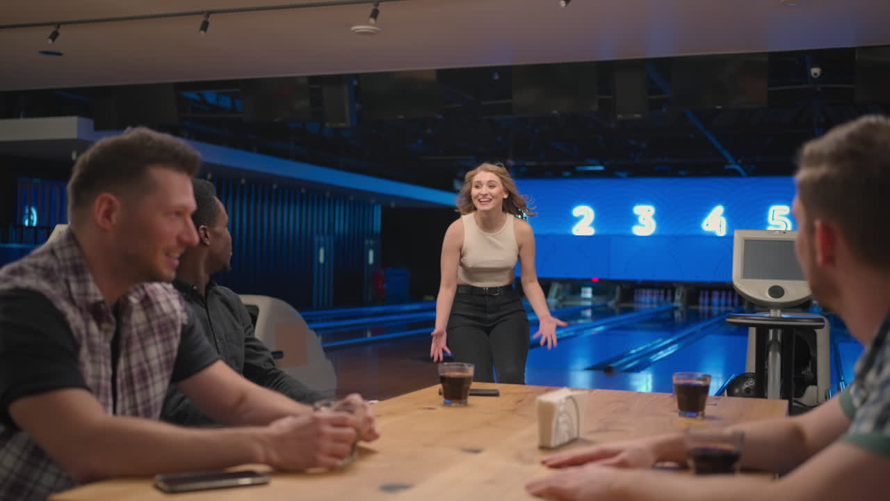 A woman in a bowling club happily runs to her friends to celebrate the knocked out clash. Share the victory with friends. Multi-ethnic group of friends