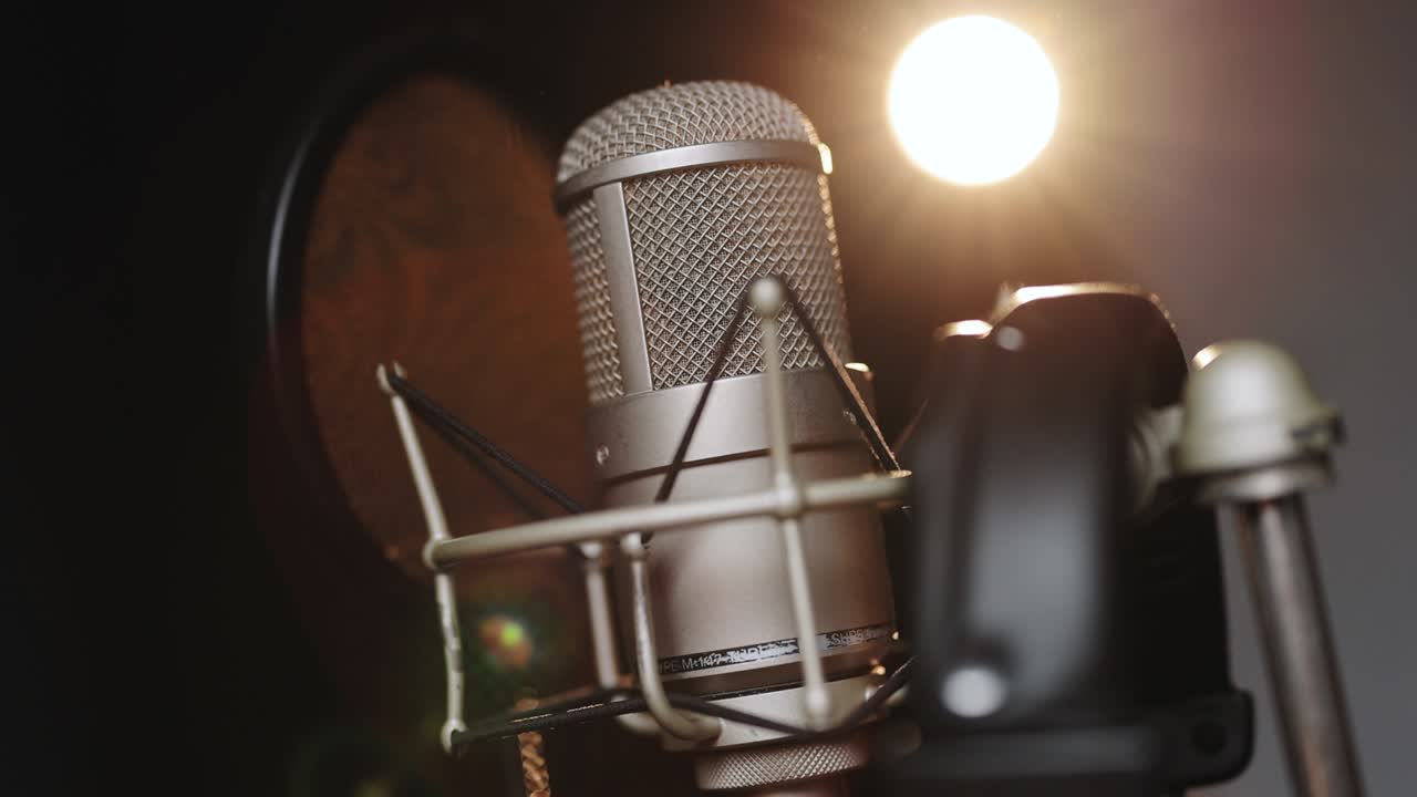 Close-up of microphone on stage against a black background with lighting. Silhouette of the microphone in the dark. Music instrument concept. Podcast, radio, interview, music studio recording