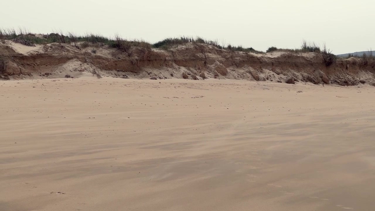 Angin meniup pasir di pantai Barbate, Andalusia, Spanyol, dengan bukit pasir yang runtuh menunjukkan erosi pantai yang disebabkan oleh perubahan iklim dan kenaikan permukaan air laut, menyoroti kerapuhan lingkungan.