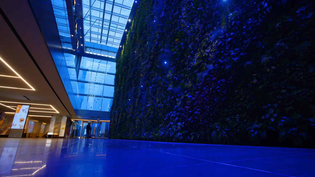 Time-lapse de personas pasando junto a un vibrante jardín vertical en un vestíbulo moderno