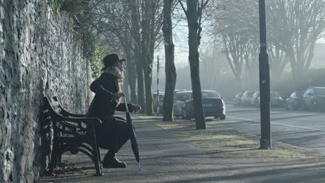 Woman-stands-up-from-bench-and-walks-down-misty-empty-street