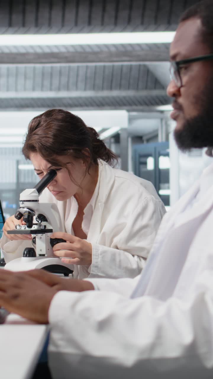 Vertical video Clinical lab technologist uses scientific microscope for disease detection