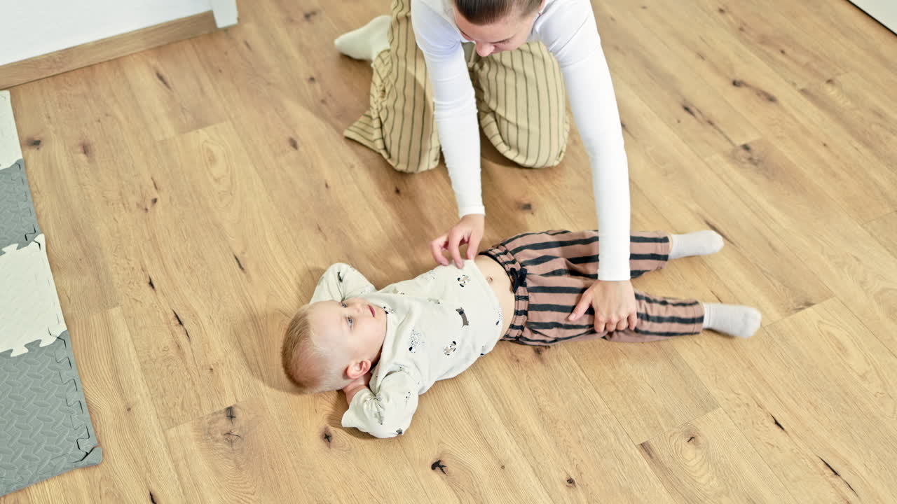 Madre allegra che gioca con il suo bambino a casa. Il bambino corre per l'appartamento e si diverte a giocare con la sua amorevole madre. Una donna in congedo di maternità trascorre del tempo con il figlio