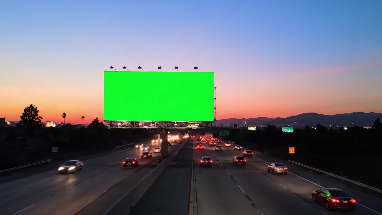 Un viaje al anochecer: Escenas cautivadoras de tráfico en una autopista dominada por una valla publicitaria de pantalla verde al atardecer y al caer la noche.