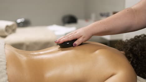 masseuse applying hot stone on client's back