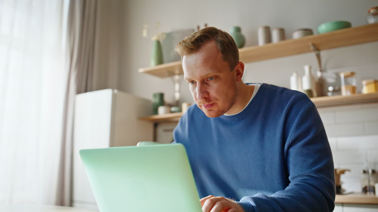 Online manager eating sandwich working laptop sitting apartment kitchen closeup