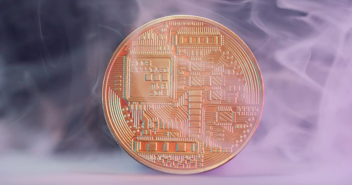 Primo piano di una moneta di criptovaluta dorata circondata dal fumo