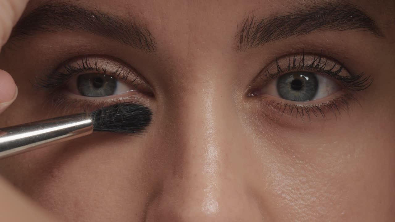 ojos de mujer de cerca aplicando maquillaje máscara con pincel concepto de cosméticos de belleza