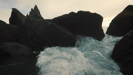 waves crashing against black rocks in iceland