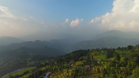 cinematic aerial dolly above terraced fields to sprawling mist covered mountains in nepal