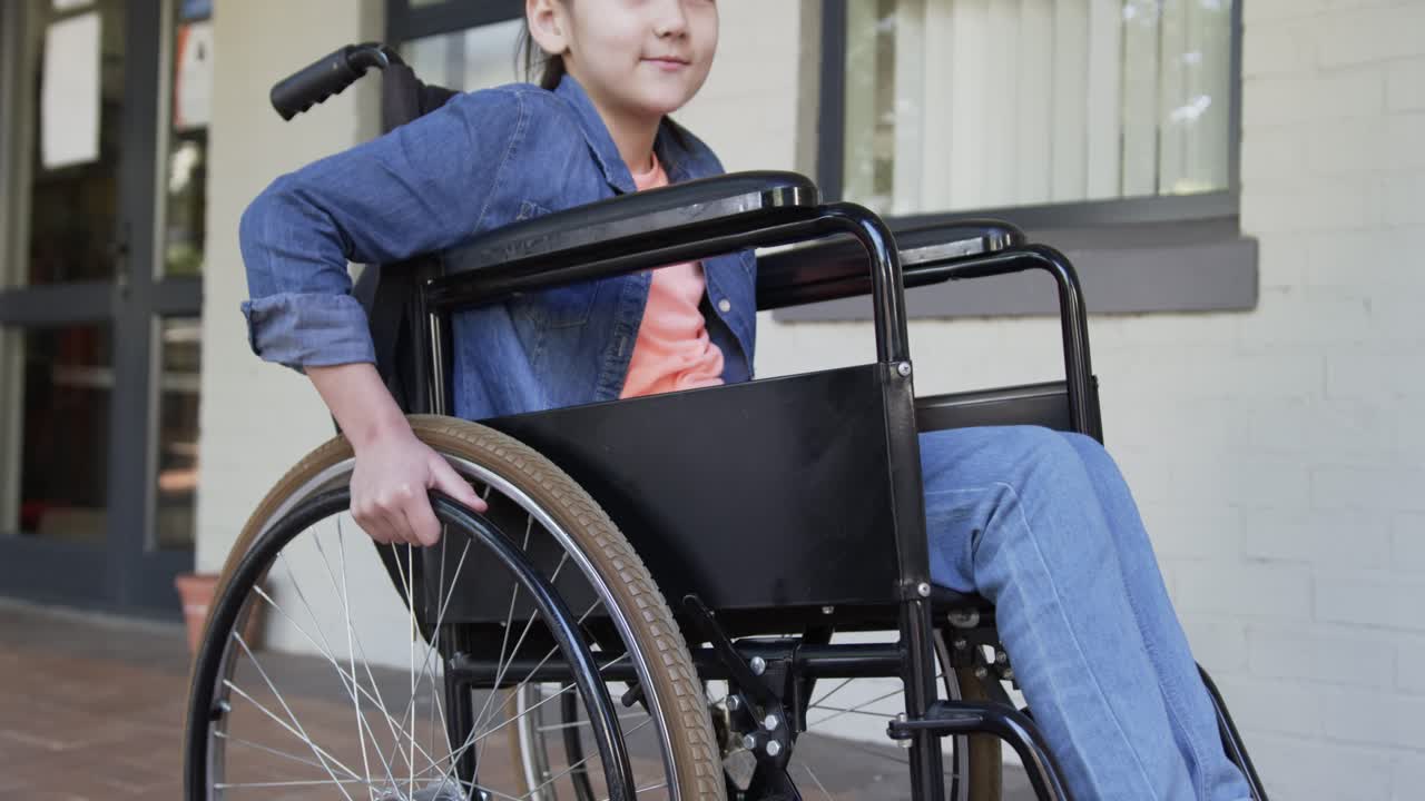 Right hand touching rim is initiating teen female pushing manual wheelchair toward door on porch
