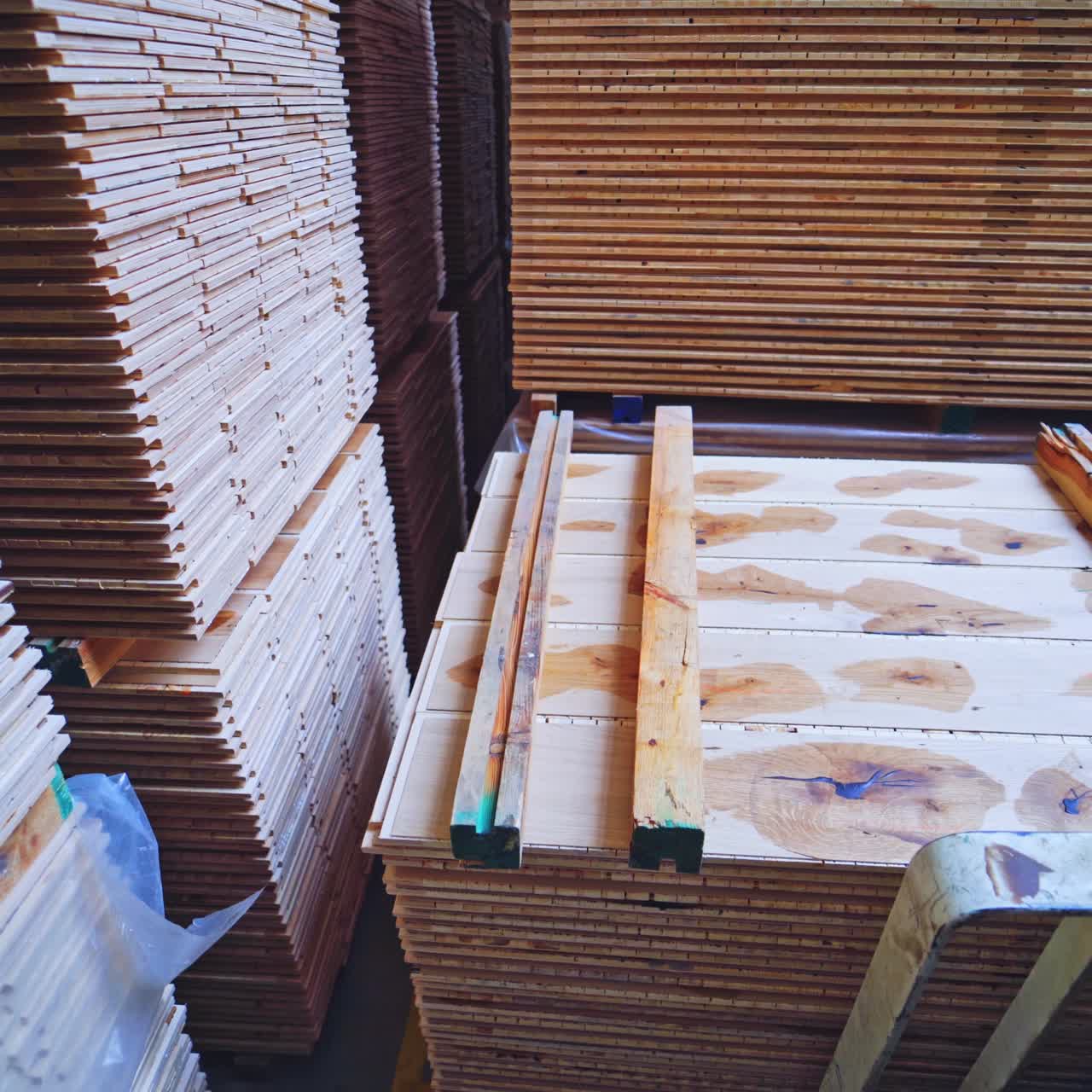 Wooden boards for flooring in the factory. Forklift cart putting pile of parquet panels inside the warehouse. Production of furniture.