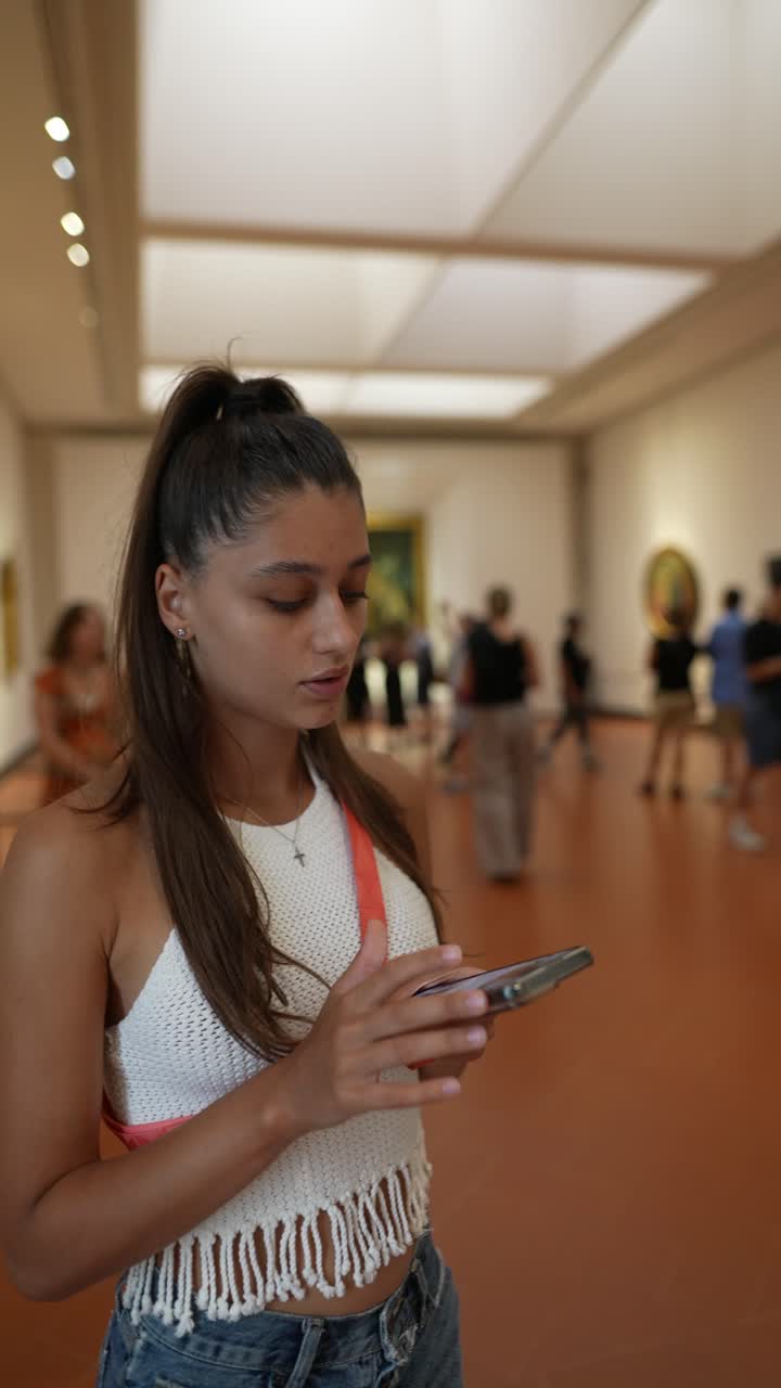 mujer viendo arte en un museo con un teléfono inteligente