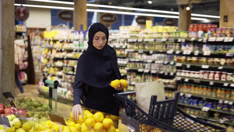 Mujer-Musulmana-Comprando-Comestibles,-Tomando-Limones-Del-Pasillo-De-Frutas