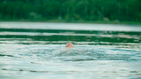 View-of-young-kid-swimming-with-backstroke-style-on-the-lake-with-nature-view-on-the-background