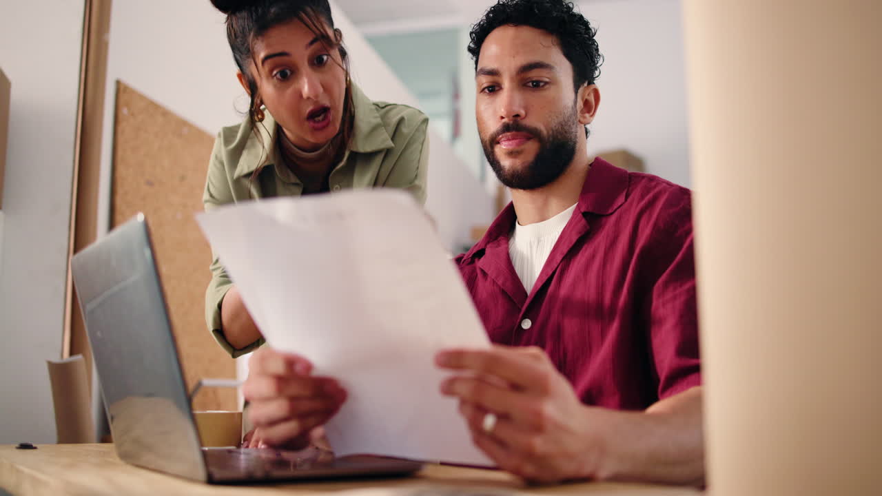 Woman and Man Discussing Documents and Laptop in Office