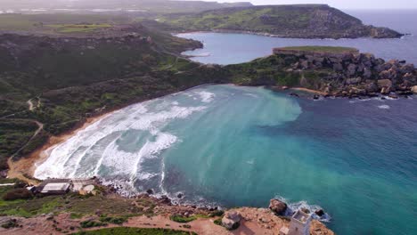 Drone-footage-showing-dramatic-waves-crashing-into-cliffs-with-lush-greenery-around