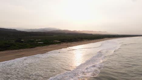 Eine-Drohne-Senkt-Sich-über-Einem-Golden-Leuchtenden-Lichtstrahl-über-Die-Meereswellen,-Die-Am-Strand-Von-Puerto-Escondido,-Oaxaca,-Mexiko,-Brechen