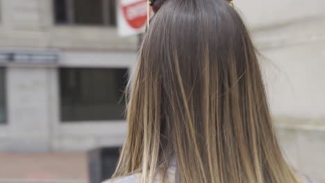 confident woman walks outside in america adjusting black face mask to be safe