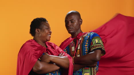 una pareja afroamericana posando con una capa roja de superhéroe