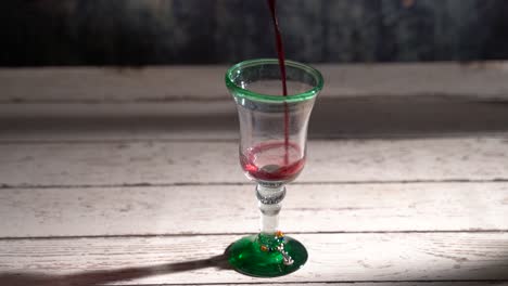 clip de vino tinto en bucle sin costuras que se vierte en un vaso rústico con fondo azul