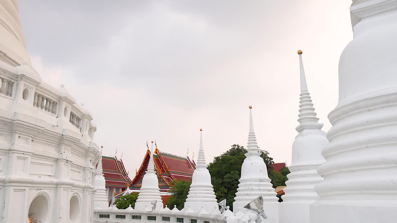Una scena tranquilla di Wat Prayurawongsawat a Bangkok, che mostra le sue iconiche pagode bianche e l'architettura tradizionale sotto una luce diurna soffusa