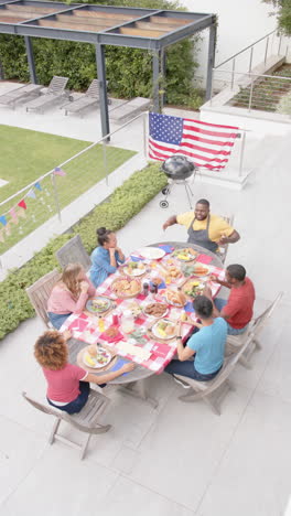 diverse friends chat and dine at garden table in slow-motion vertical video