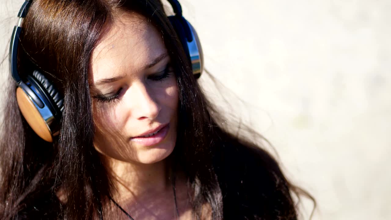 verano, contra el fondo del mar. mujer hermosa, con cabello largo y oscuro, escuchando música en auriculares de un teléfono móvil, dispositivo, al aire libre, bailes. disfrutando de la música