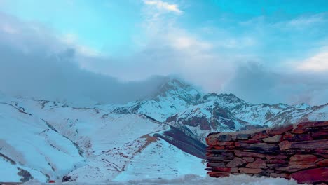 view of the top of mount kazbegi from behind a brick wall