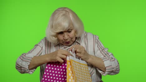 abuela sosteniendo bolsas de compras, regocijándose de los descuentos en la tienda, disfrutando de las compras con precios bajos