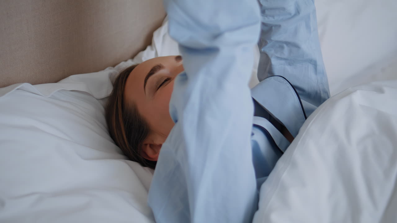 Sleepy girl lying bed at morning closeup. Lazy woman waking up in soft pillows