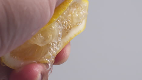 hand squeezes lemon juice on a white background, isolated