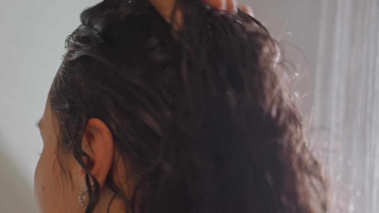 Washing hair with gentle conditioner. Applying conditioner softly to wet curly hair. Gentle cleansing and conditioning process involving careful application and massage to wet curly hair