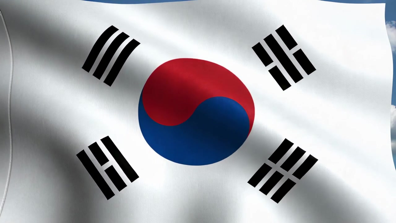 Vajende sydkoreansk flag blafrer på flagstang udendørs i brisen, viser flagøje og skyer.