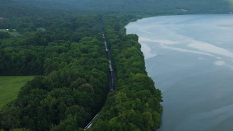 Panoramic-drone-shot-of-train-moving-alongside-Lake-Dardanelle