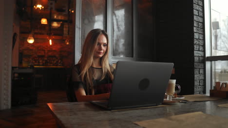 Mujer-Joven-Feliz-Tomando-Café-Y-Usando-Una-Tableta-En-La-Cafetería